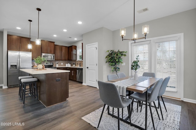 kitchen featuring tasteful backsplash, dark hardwood / wood-style floors, a kitchen island, pendant lighting, and stainless steel appliances