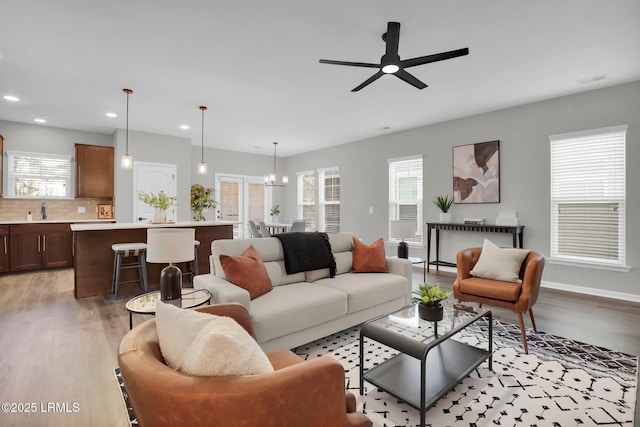 living room with sink, light hardwood / wood-style floors, and ceiling fan