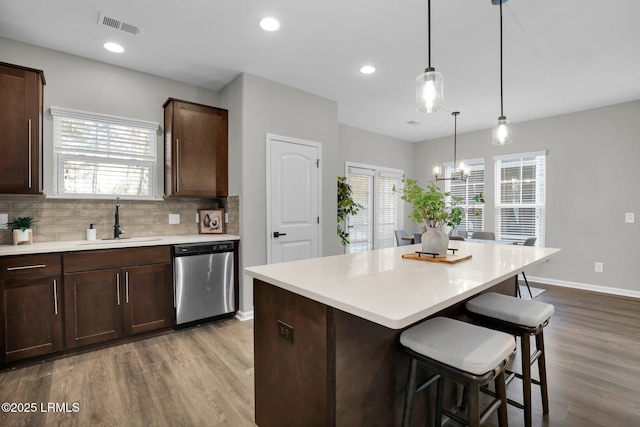 kitchen with sink, dishwasher, hanging light fixtures, tasteful backsplash, and dark brown cabinetry