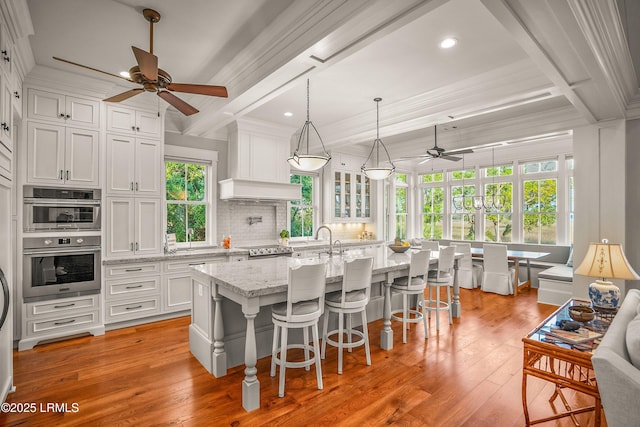 1448 Gleasons Landing Dr, Saint Helena Island, SC 29920 - kitchen featuring a ceiling fan, light wood-style flooring, a kitchen island with sink, and white cabinetry