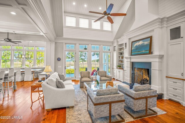 1448 Gleasons Landing Dr, Saint Helena Island, SC 29920 - living room with ceiling fan, a fireplace, built in shelves, hardwood / wood-style floors, and a towering ceiling