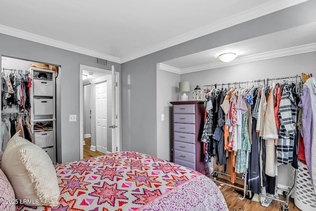 bedroom with ornamental molding, a closet, visible vents, and wood finished floors