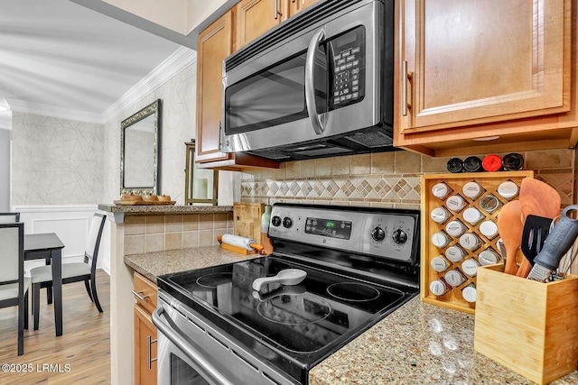 kitchen featuring decorative backsplash, ornamental molding, stainless steel appliances, and light stone counters