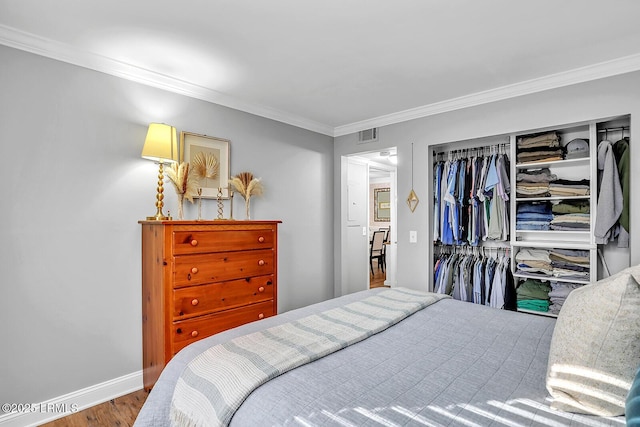 bedroom with a closet, visible vents, crown molding, and baseboards