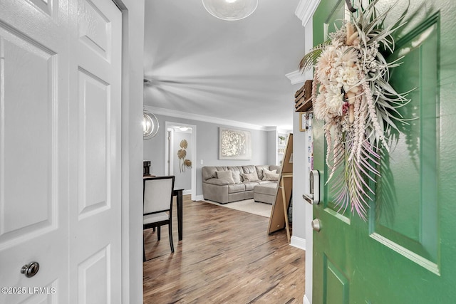 entryway featuring baseboards, crown molding, and wood finished floors