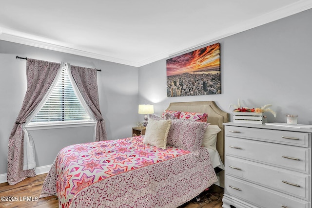 bedroom with ornamental molding, wood finished floors, and baseboards