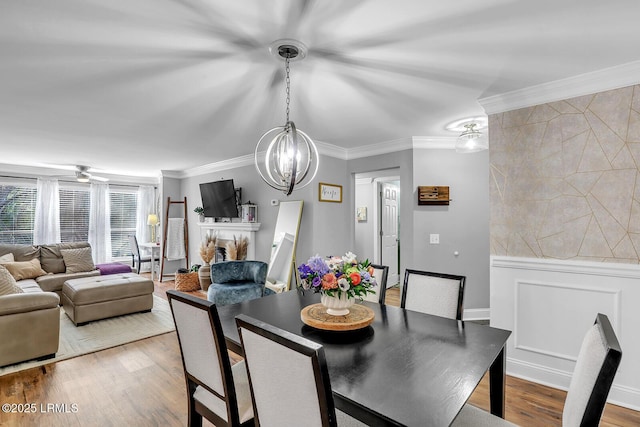 dining space with a fireplace, ornamental molding, and wood finished floors