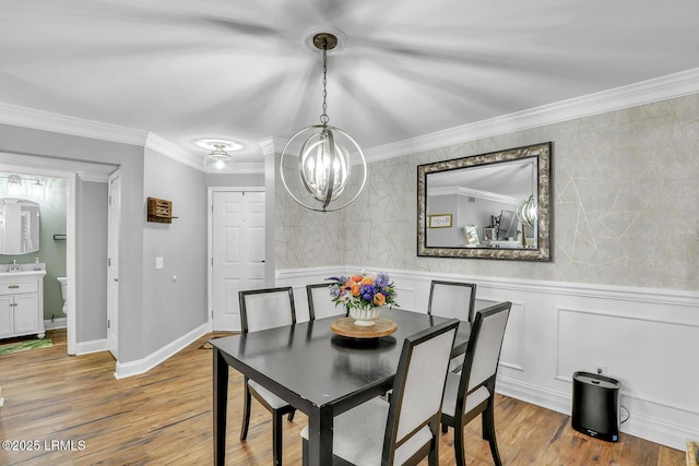 dining room featuring light wood finished floors, ornamental molding, and a notable chandelier