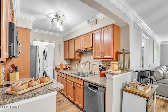 kitchen with crown molding, visible vents, appliances with stainless steel finishes, stacked washer / dryer, and a sink