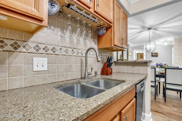 kitchen with a sink, black dishwasher, hanging light fixtures, decorative backsplash, and crown molding