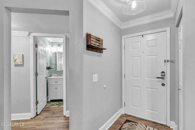 entrance foyer with light wood-type flooring, crown molding, and baseboards