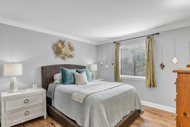 bedroom featuring baseboards, crown molding, and light wood finished floors