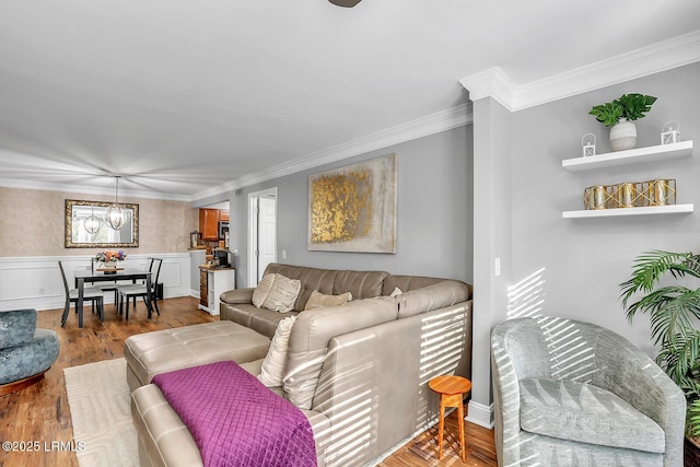 living area featuring ornamental molding, wainscoting, wood finished floors, and a notable chandelier