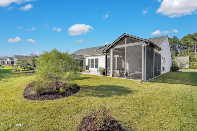 back of house with a patio area, a sunroom, and a lawn