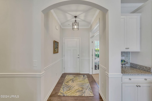 foyer with dark wood-type flooring and ornamental molding