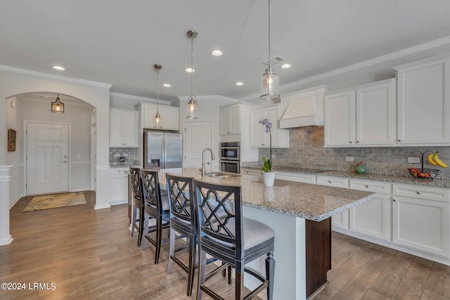 kitchen with an island with sink, appliances with stainless steel finishes, white cabinets, and decorative backsplash