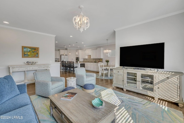 living room featuring crown molding, light hardwood / wood-style floors, and a notable chandelier