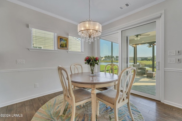 dining area with crown molding, ceiling fan with notable chandelier, dark hardwood / wood-style floors, and a water view