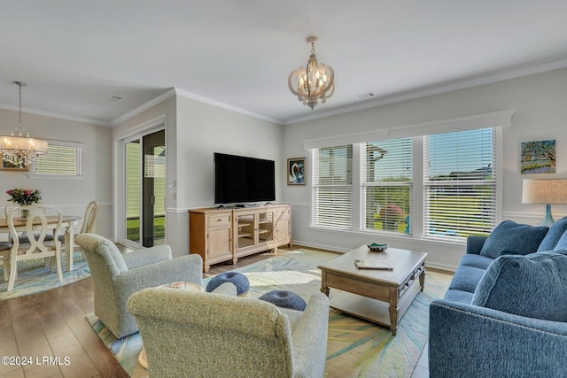 living room with an inviting chandelier, ornamental molding, a healthy amount of sunlight, and light hardwood / wood-style floors