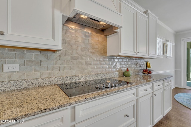 kitchen with custom exhaust hood, light stone countertops, black electric stovetop, and white cabinets