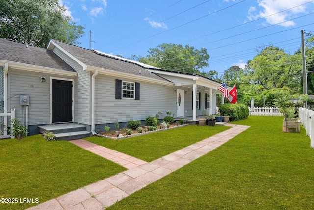 view of front facade with a shingled roof, a porch, fence, and a front lawn