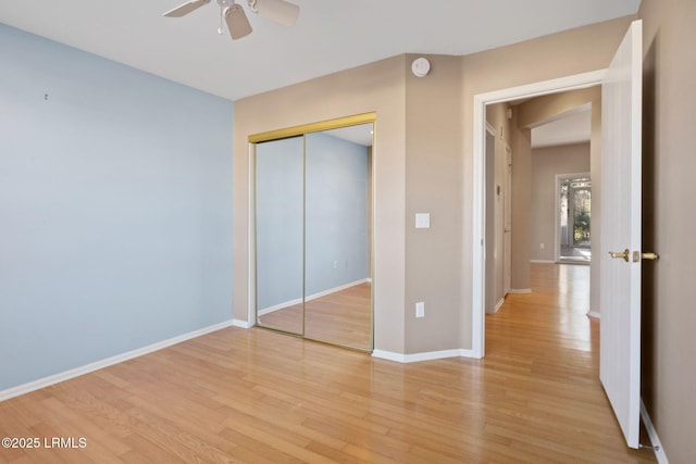 unfurnished bedroom with ceiling fan, a closet, and light wood-type flooring