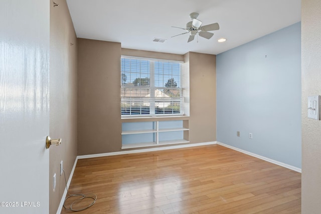 unfurnished room featuring built in shelves, light hardwood / wood-style floors, and ceiling fan