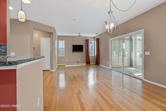 interior space featuring ceiling fan with notable chandelier and light wood-type flooring