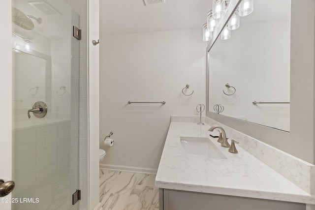 bathroom with toilet, vanity, and a shower with shower door