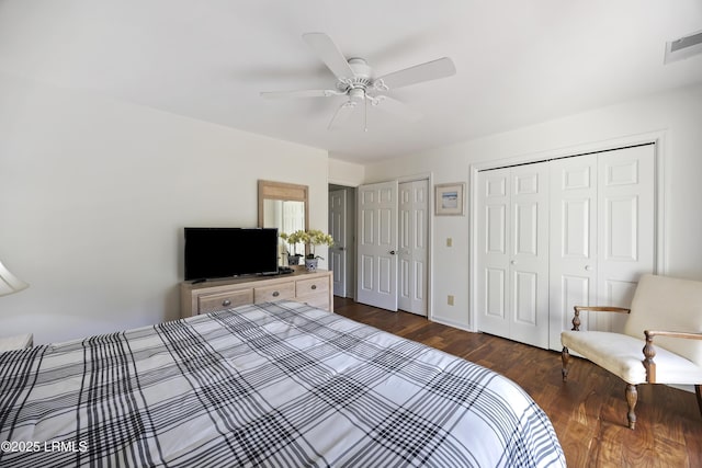 bedroom with multiple closets, dark hardwood / wood-style flooring, and ceiling fan