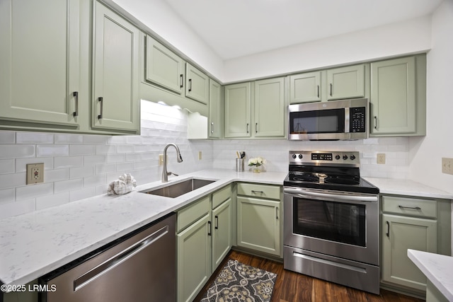 kitchen with green cabinetry, stainless steel appliances, sink, and decorative backsplash