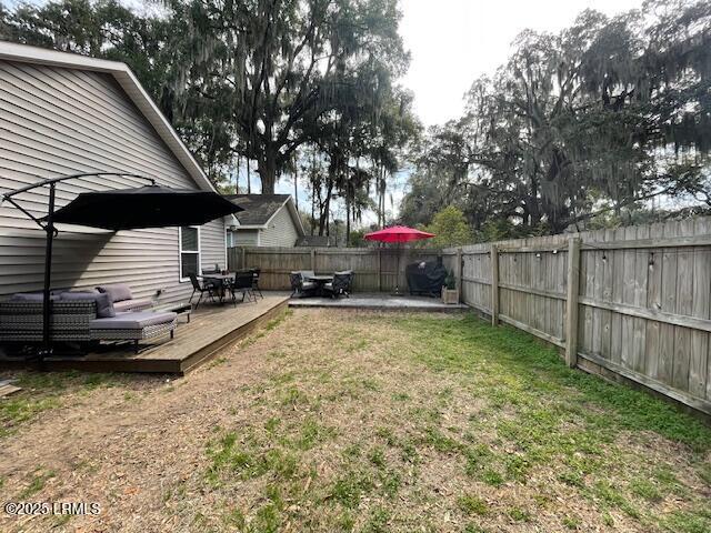 view of yard featuring a wooden deck and a patio