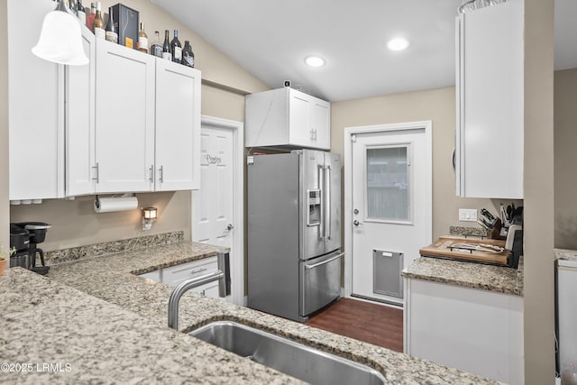 kitchen featuring sink, white cabinetry, stainless steel fridge with ice dispenser, light stone countertops, and stove