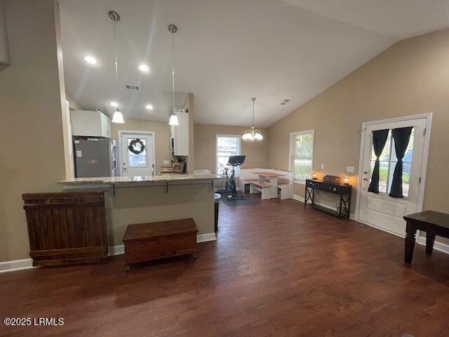 kitchen with stainless steel refrigerator with ice dispenser, a kitchen bar, decorative light fixtures, kitchen peninsula, and white cabinets