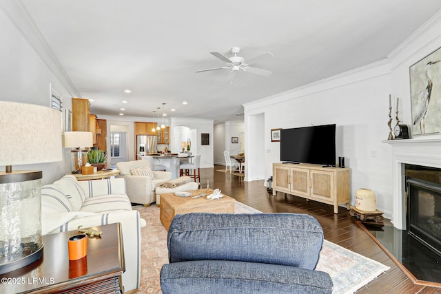 living room with dark hardwood / wood-style flooring, crown molding, and ceiling fan