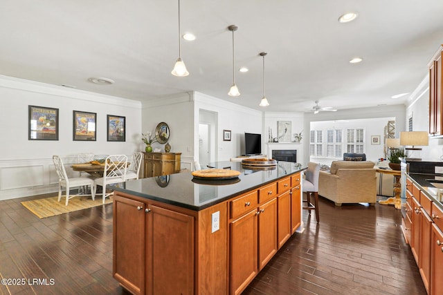 kitchen with a kitchen island, hanging light fixtures, ornamental molding, ceiling fan, and dark wood-type flooring