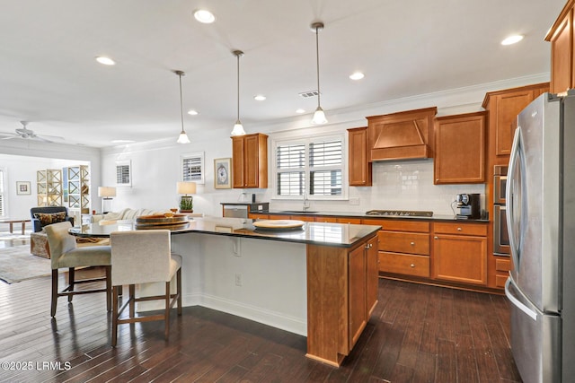 kitchen with dark wood-type flooring, appliances with stainless steel finishes, a center island, decorative light fixtures, and custom exhaust hood