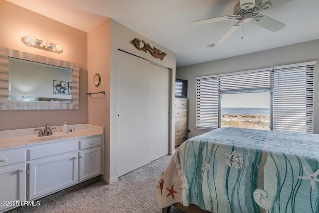 bedroom with light carpet, a sink, a ceiling fan, and a closet