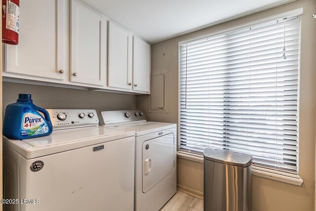 laundry room with washer and clothes dryer, light wood finished floors, baseboards, cabinet space, and plenty of natural light