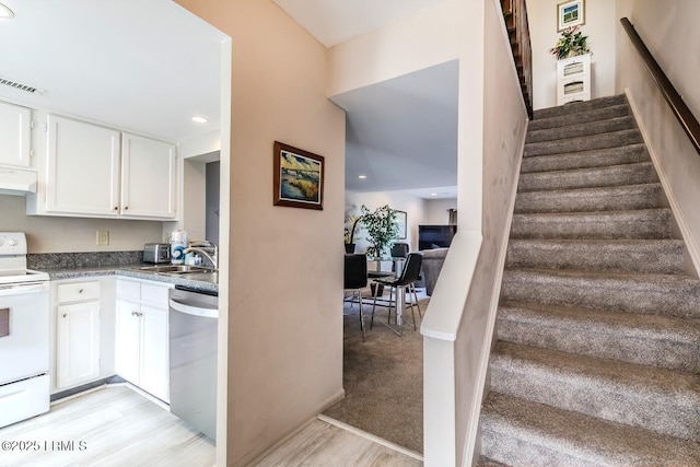 kitchen with stainless steel dishwasher, white electric range oven, under cabinet range hood, white cabinets, and light wood-style flooring