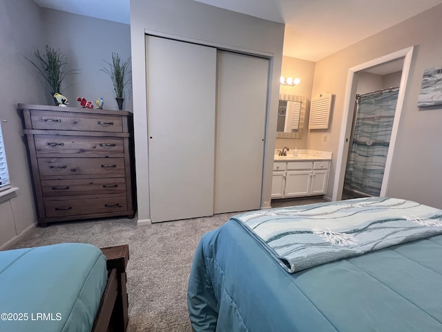 carpeted bedroom with a closet, a sink, ensuite bath, and baseboards