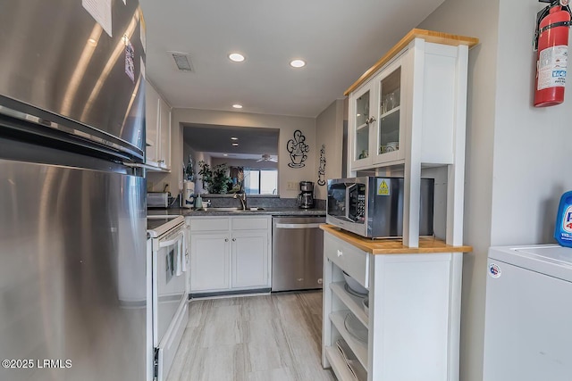 kitchen featuring stainless steel appliances, butcher block countertops, washer / clothes dryer, a sink, and glass insert cabinets
