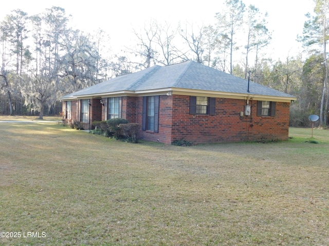 view of property exterior featuring brick siding, a shingled roof, and a yard