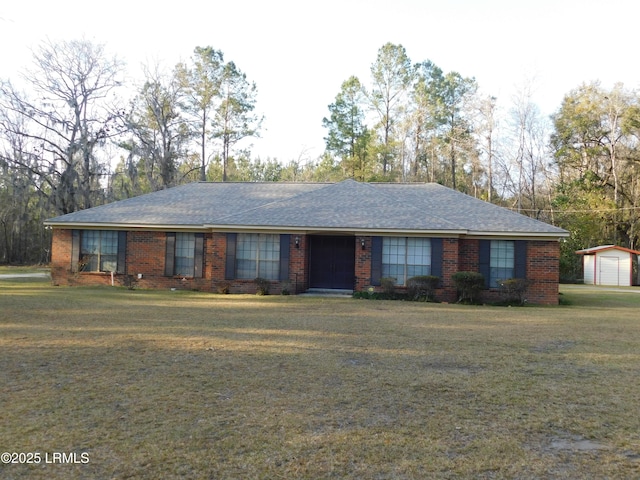 ranch-style home featuring brick siding, an outdoor structure, a front lawn, and a shingled roof