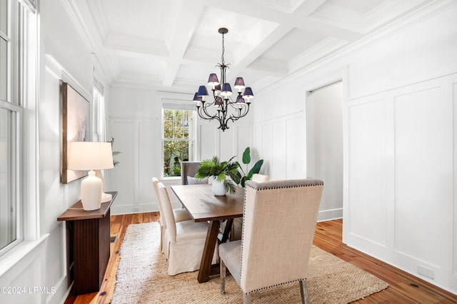 dining space featuring beam ceiling, coffered ceiling, a notable chandelier, and light hardwood / wood-style floors