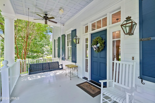 view of exterior entry with ceiling fan and a porch