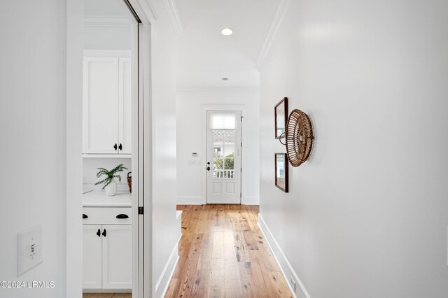 doorway to outside featuring crown molding and light wood-type flooring