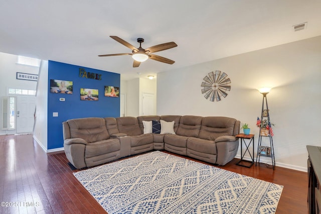 living room with dark wood-style floors, visible vents, ceiling fan, and baseboards