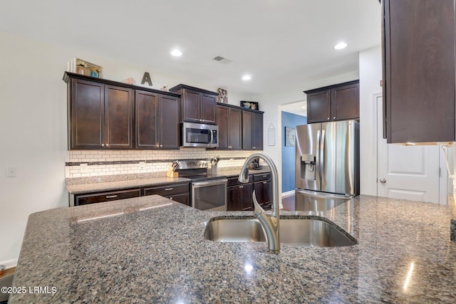 kitchen with tasteful backsplash, visible vents, dark stone counters, stainless steel appliances, and a sink