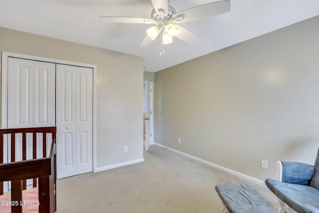 bedroom featuring light carpet, ceiling fan, a closet, and baseboards